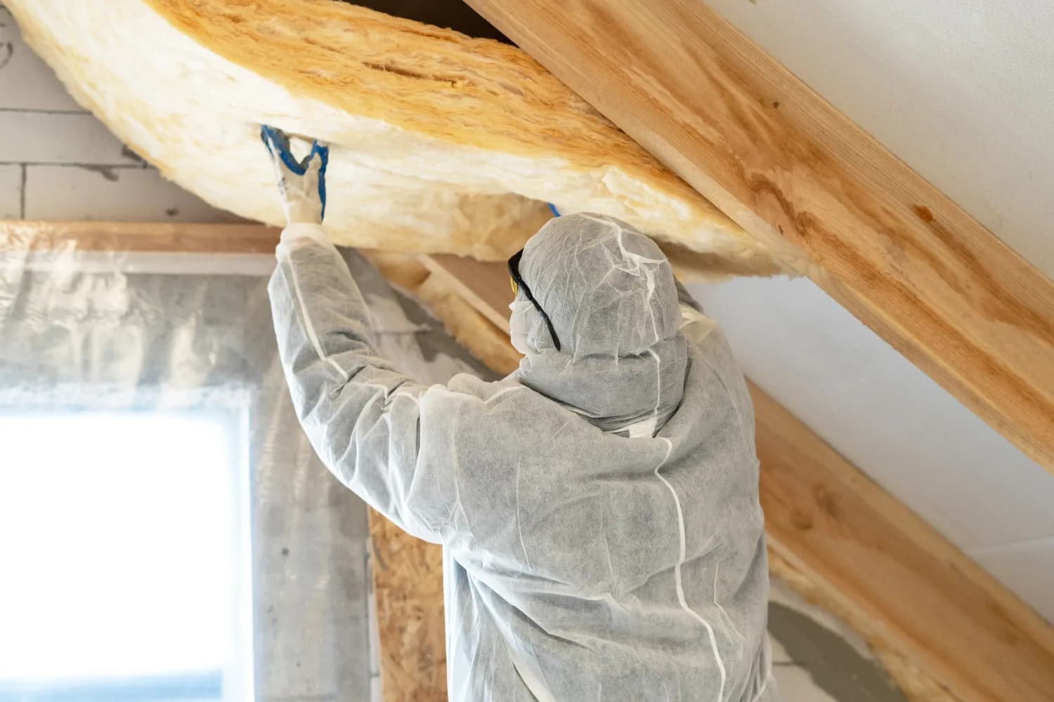 Insulation being installed along a sloped attic ceiling