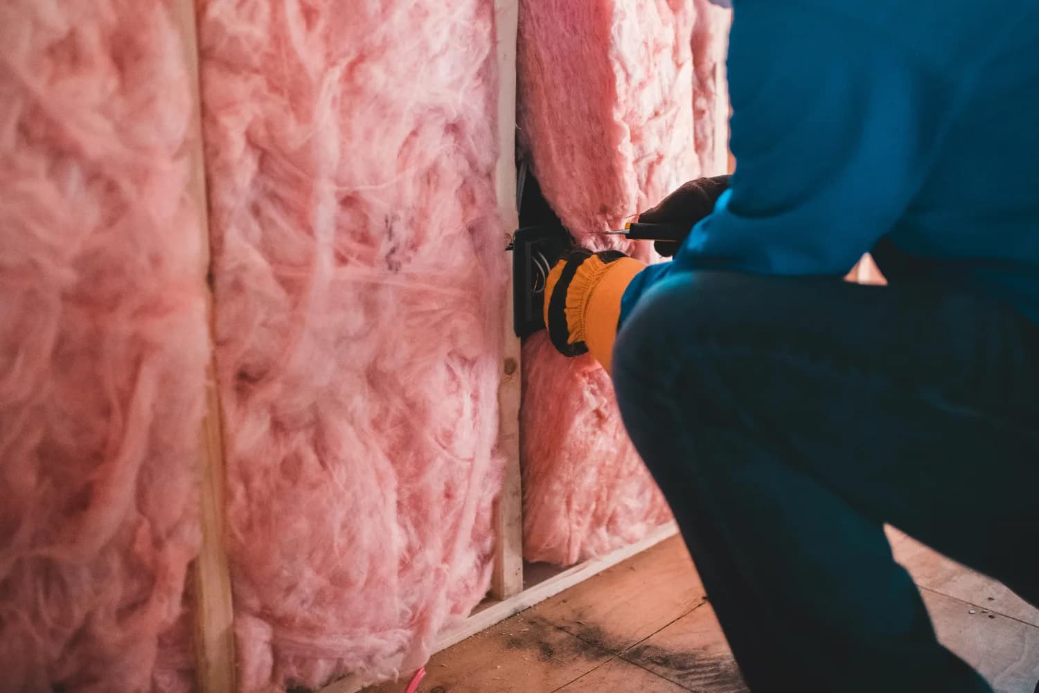 Installer fitting batt insulation into a wall cavity