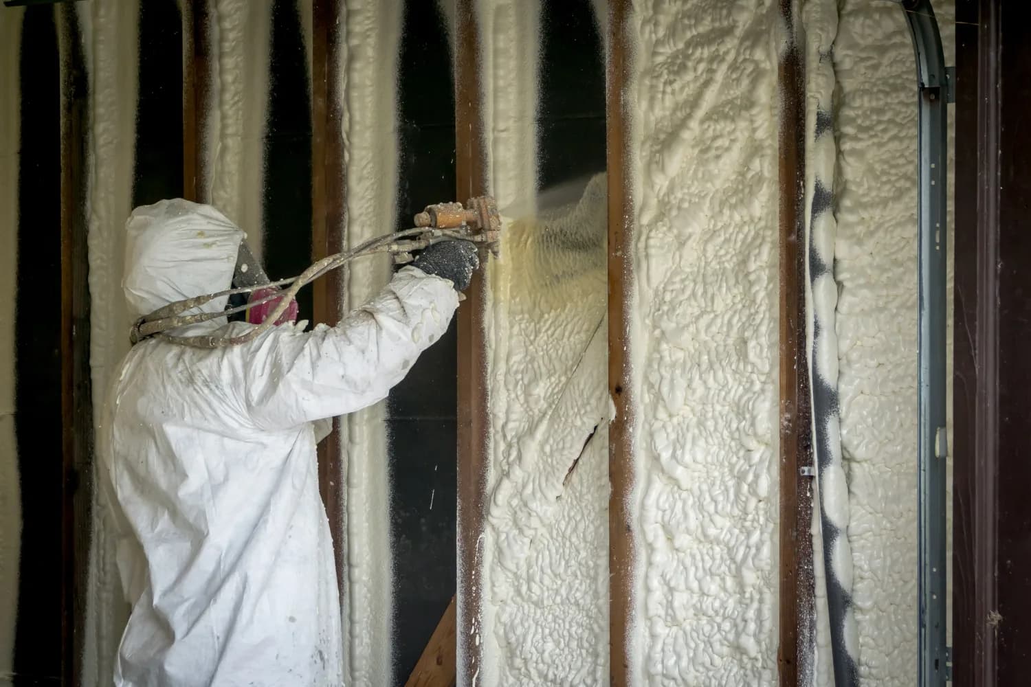 Technician spraying foam insulation into wall cavities